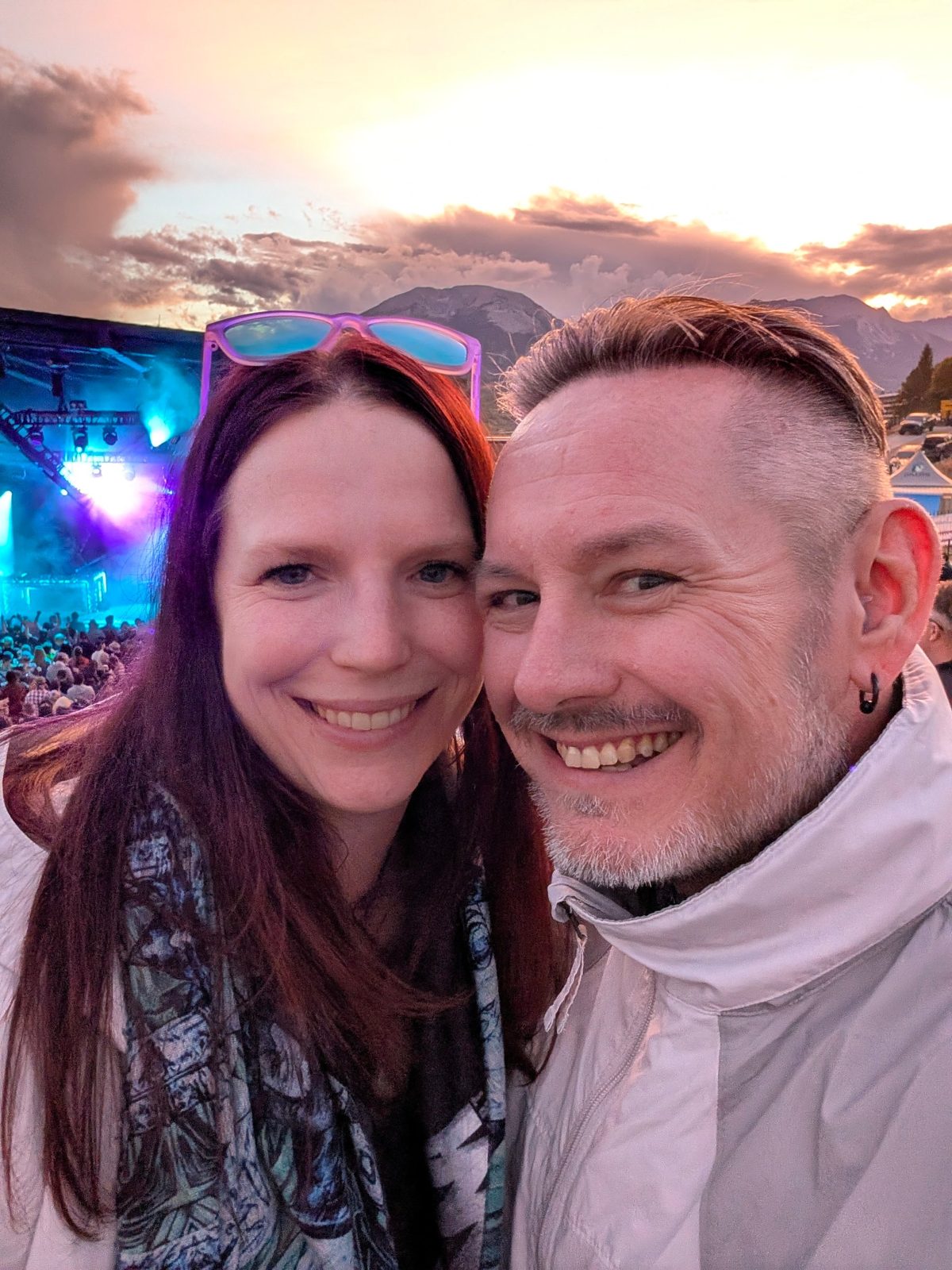 Hannah and Brad cheek to cheek at a mountain concert at sunset